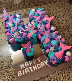 a birthday cake with cupcakes and decorations on it