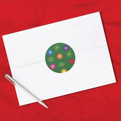 an envelope with a christmas ornament on it and a pen next to it