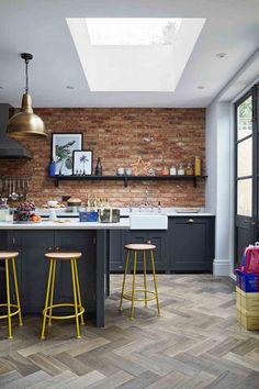 a kitchen with two stools in front of the counter and an open skylight