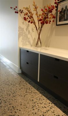 a vase with some red flowers in it sitting on a shelf next to a wall