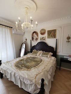 a bedroom with a bed, chandelier and pictures on the wall above it