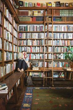 a woman sitting in front of a book shelf filled with books