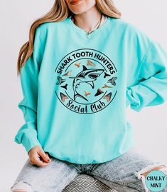 Discover our Shark Tooth Hunters Social Club Comfort Colors summer beach vacation crewneck Sweatshirt! This trendy high quality Unisex Shark Tooth Sweatshirt is Comfort Colors NEW light weight design! It is super soft and comfortable made of 100% ring-spun ethically grown cotton. It has a relaxed fit that is made of a light weight fabric. Looks super cute with shirts, jeans or size up 1 to 3 sizes for an oversized beach cover up. Great gift idea for a Birthday or a Shark lover! Comes in 14 prett Beachy Sweater, Shark Gifts, Beach Sweatshirt, Shark Lover, Summer Beach Vacation, Shark Shirt, Shark Tooth, Shark Teeth, Comfort Wear