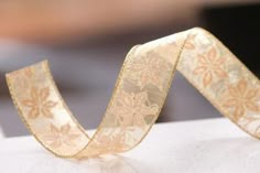 a roll of gold ribbon on top of a white table cloth with a blurry background