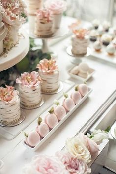 there are many small cakes and desserts on the table with pink flowers in them