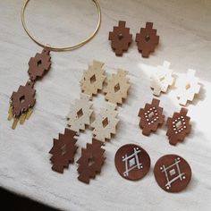 several wooden pieces are laid out on a white tablecloth, including earrings and pendants