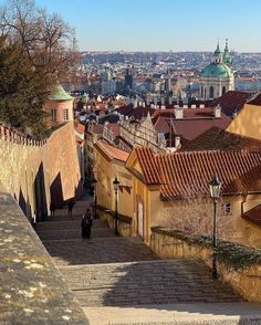 a man walking up some stairs in an old city with lots of buildings on either side