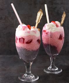 two glasses filled with ice cream and strawberries on top of each other in front of a dark background