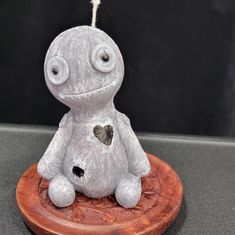 a small white stuffed animal sitting on top of a wooden plate with a heart in it's eyes