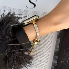 a woman's arm with an apple watch on top of it and some feathers