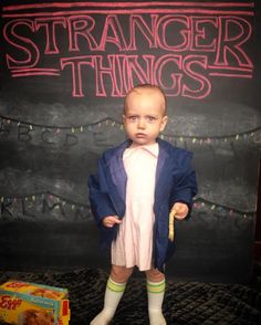 a baby standing in front of a chalkboard with the words strange things written on it