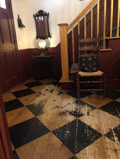 a chair sitting on top of a checkered floor next to a wooden banister