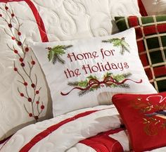 a bed with red and white comforter, pillows and christmas decorations on the pillow