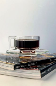 a stack of magazines with a cup of coffee on top