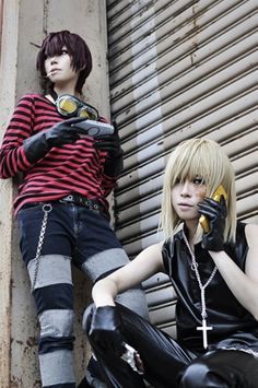 two young men sitting next to each other in front of a wall with graffiti on it