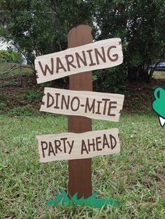 a wooden sign that says warning dino - mite party ahead on it in the grass