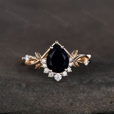 a black and white diamond ring sitting on top of a stone surface with gold accents