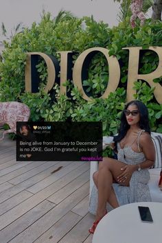 a woman sitting on top of a white couch next to a wooden sign that says dior