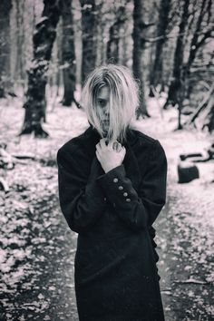 a woman standing in the woods with her hands on her chest and looking down at her face