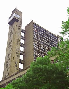 the tall building has many balconies on it's sides and is surrounded by trees