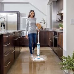 a woman is cleaning the floor in her kitchen with a mop and vacuum cleaner