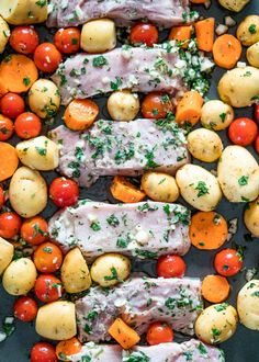 chicken, potatoes and tomatoes on a sheet pan with parsley sprinkled on top