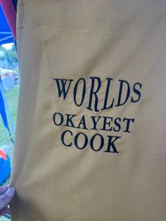 a person holding a bag with the words world's okayest cook on it