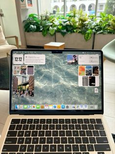 an open laptop computer sitting on top of a table next to a potted plant