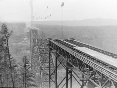 an old photo of a train going over a bridge in the mountains on a foggy day