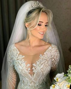 a woman in a wedding dress holding a bouquet and smiling at the camera while wearing a tiara