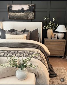 a white bed sitting in a bedroom next to a night stand with flowers on it