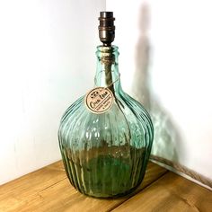 a green glass bottle sitting on top of a wooden table