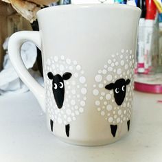 a white coffee cup with black sheep painted on it