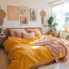 a bed with yellow sheets and pillows in a room next to a window filled with potted plants