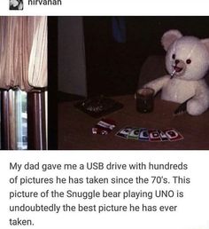 a white teddy bear sitting on top of a table next to a cup and playing uno