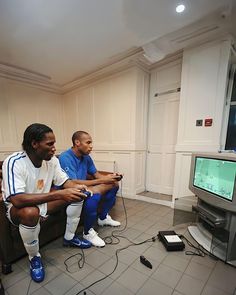 two men sitting in front of a tv playing video games on the nintendo wii while another man watches