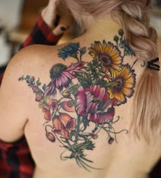 a woman's back with flowers on her shoulder and chest tattooing the upper half of her body