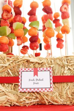 a basket filled with fruit on top of a red table cloth covered in hay and straw