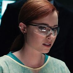 a woman wearing glasses looking at something in her hand