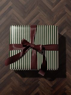 a present wrapped in brown and white striped paper with a red ribbon on top of it