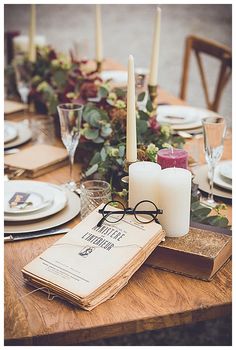 the table is set with candles, books, and glasses for dinner guests to enjoy