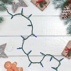 christmas decorations and presents are laid out on a white wooden table with pine cones, twine lights, and ornaments