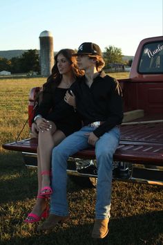 two women sitting on the back of a pickup truck