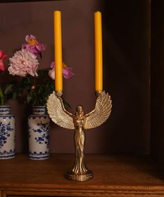 two candles are sitting on a table next to some vases with flowers in them