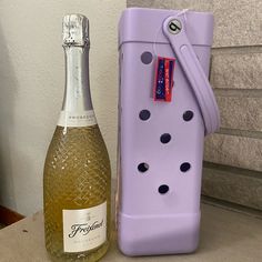 a bottle of wine sitting next to a purple case with holes on it and a corkscrew