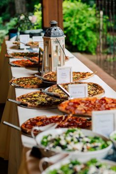 a long table filled with lots of different types of pizzas and salads on it