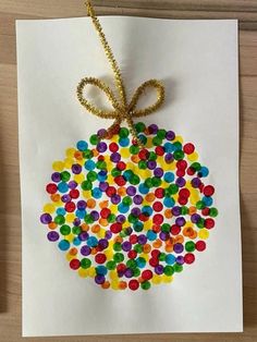 an ornament made out of gummy dots on paper with a gold ribbon