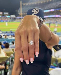 a close up of a person's hand with a diamond ring on it at a baseball game