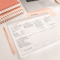 a desk with a notebook, pen and laptop on it next to an open planner