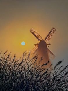 the sun is setting behind a windmill